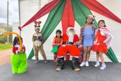 Children wearing festive costumes alongside Santa Claus during Christmas in Saylla, 2024