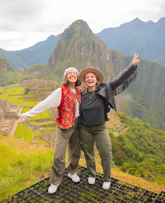 Two smiling travelers in front of the citadel of Machu Picchu, Cusco