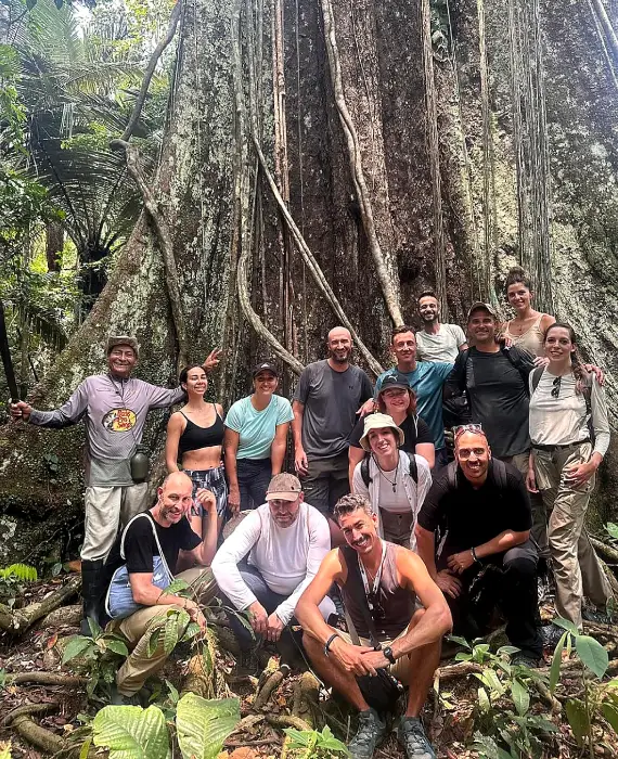 Travelers beside a large tree in Peru's tropical forest