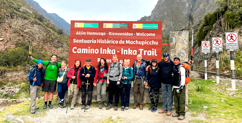 Classic Inca Trail panoramic view showing terraced mountainsides, ancient stone ruins, and dramatic Andean peaks with morning mist and golden sunlight