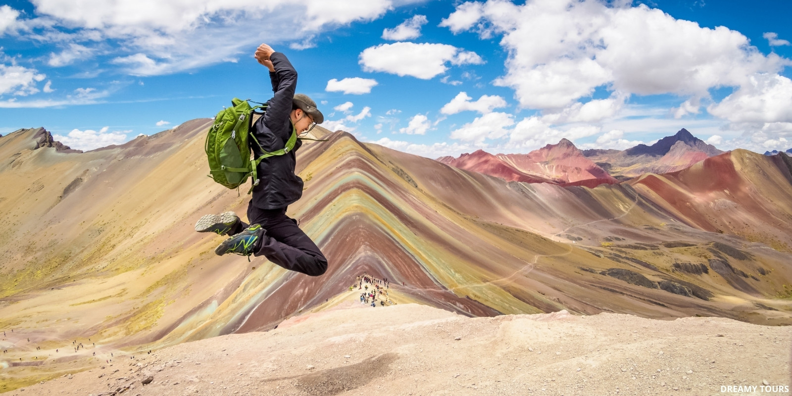 Montaña de Siete Colores, Vinicunca, Perú, con laderas coloridas y viajera saltando de la emoción