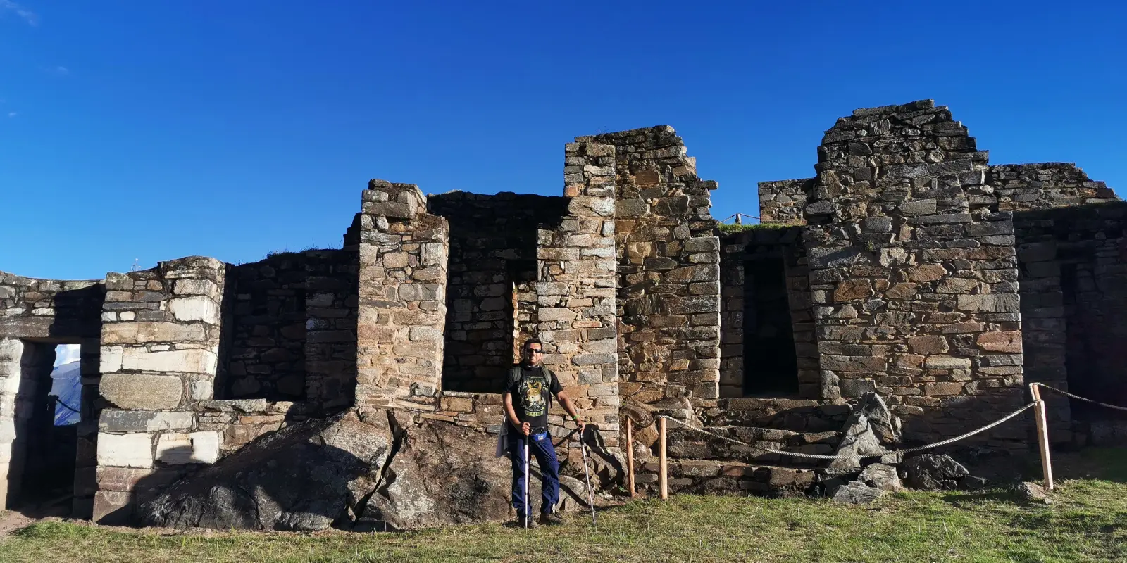 Turista posa frente a las ruinas incaicas de Choquequirao. Muros de piedra antiguos bajo un cielo azul en los Andes peruanos