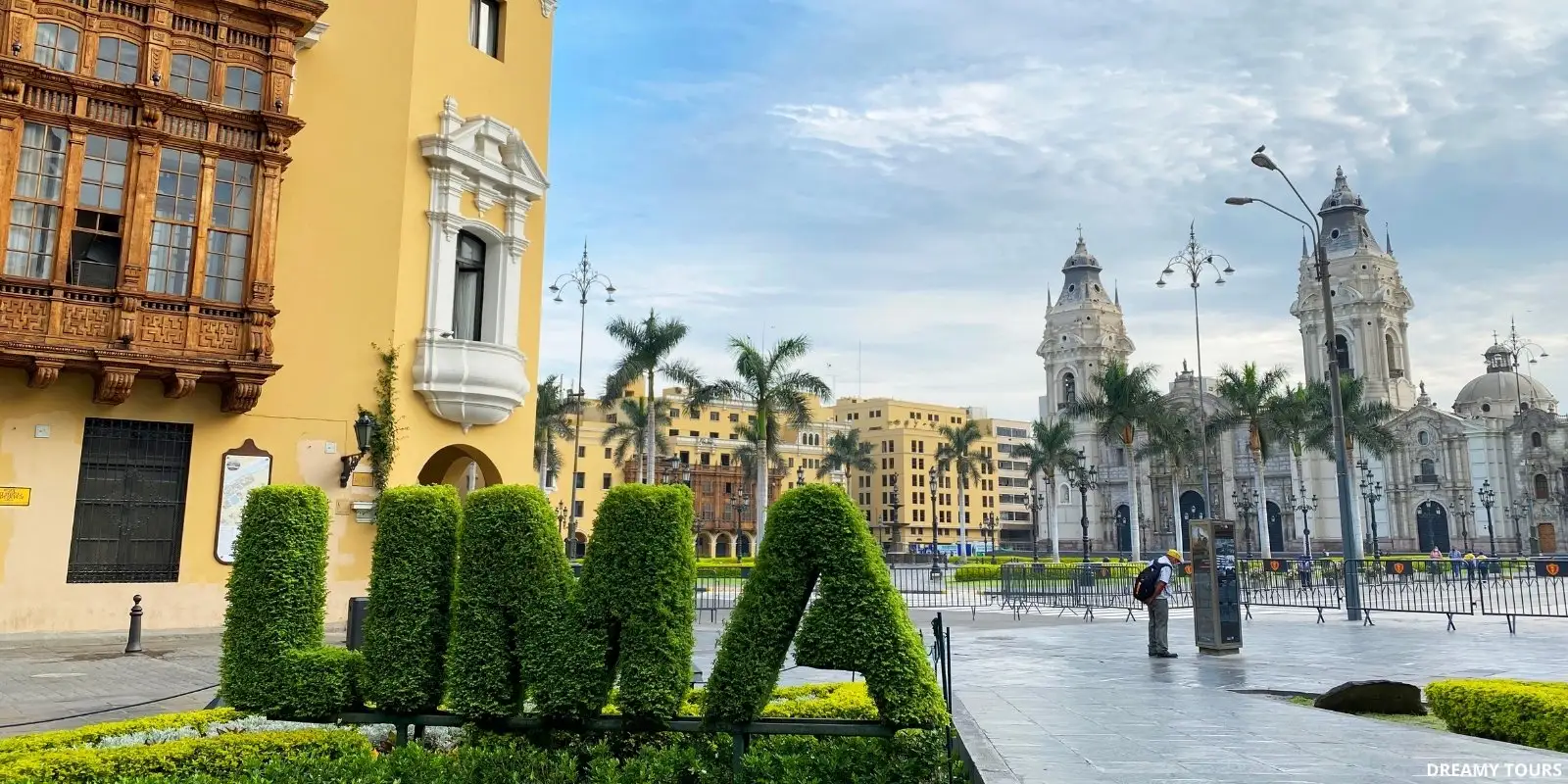 Lima's Plaza Mayor with its historical fountain and the Cathedral under a blue sky.