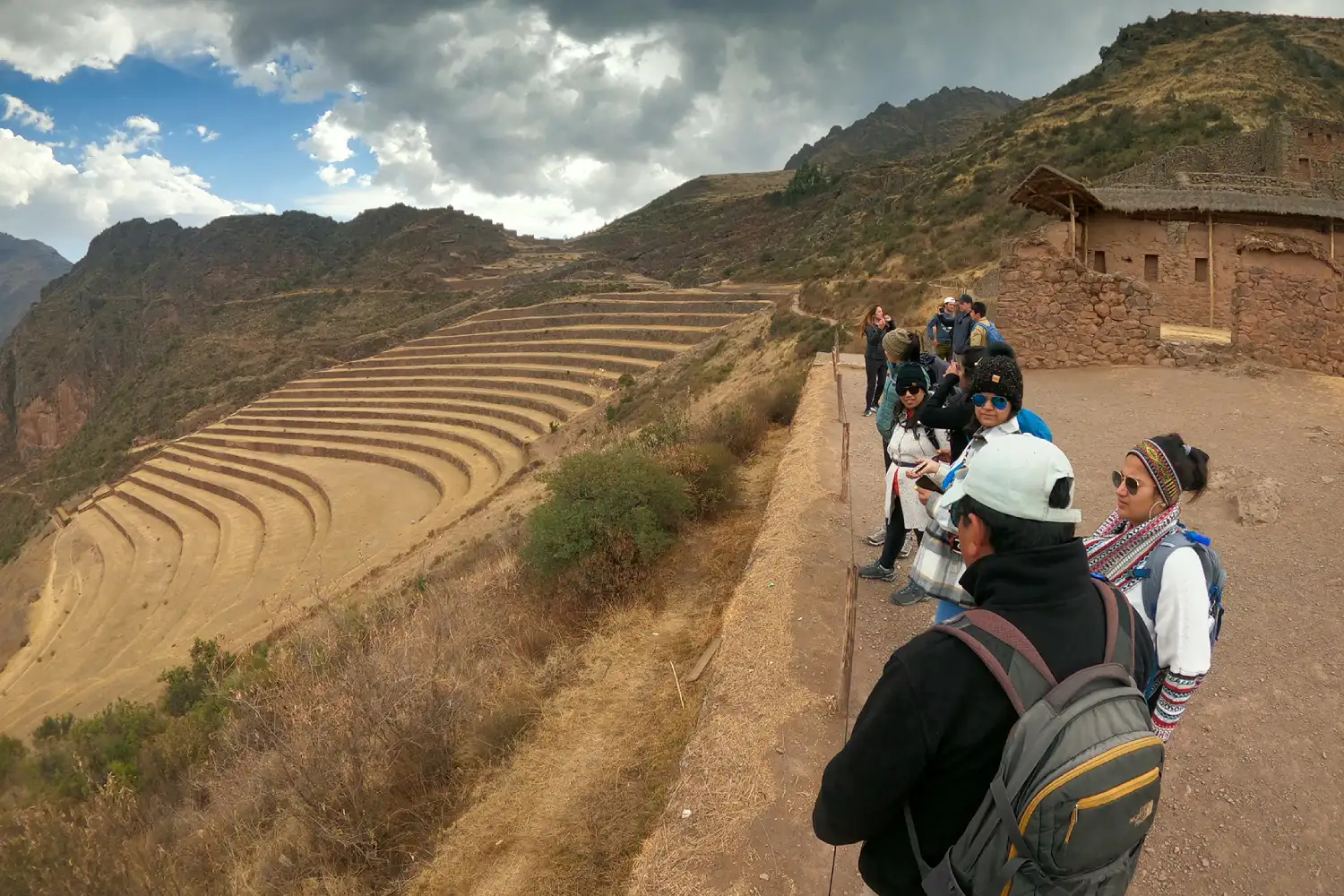 Grupo de viajantes contemplando o centro arqueológico de Pisac.